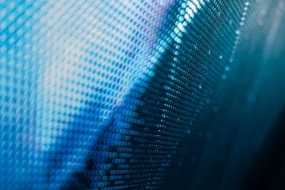 Close-up of a blue abstract digital surface made of small glowing dots forming wave-like patterns.